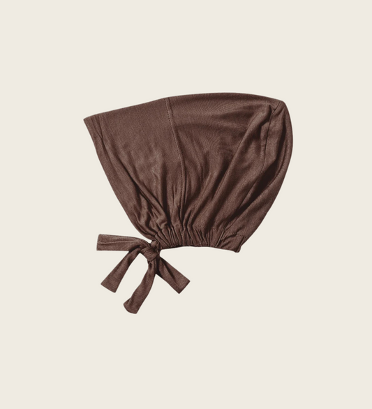 A dark brown tie-back hijab cap made from soft fabric, designed to hold a hijab in place.